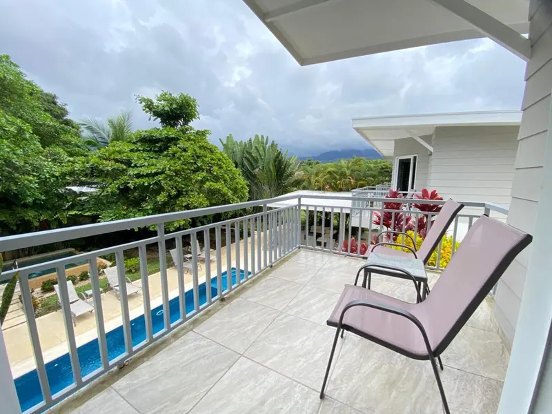 Terrasse carrelée avec transats et vue sur la végétation luxuriante.