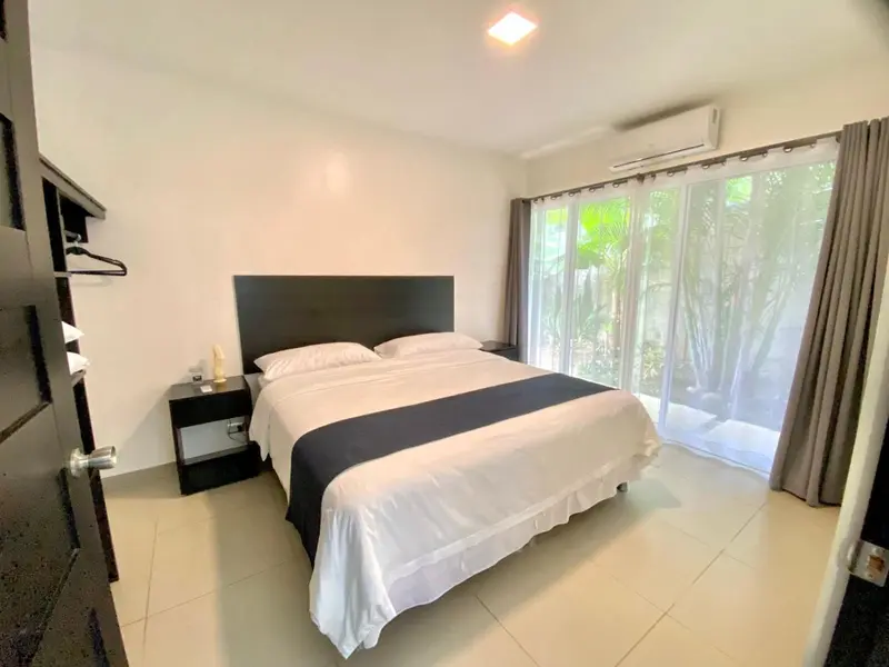 Une chambre lumineuse avec un grand lit et un accès à une terrasse.