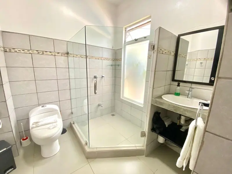 Une salle de bain claire avec douche à l'italienne et lavabo.