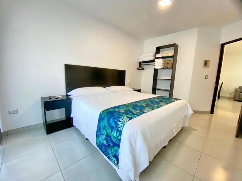 Une chambre lumineuse avec un grand lit recouvert d'une courtepointe.