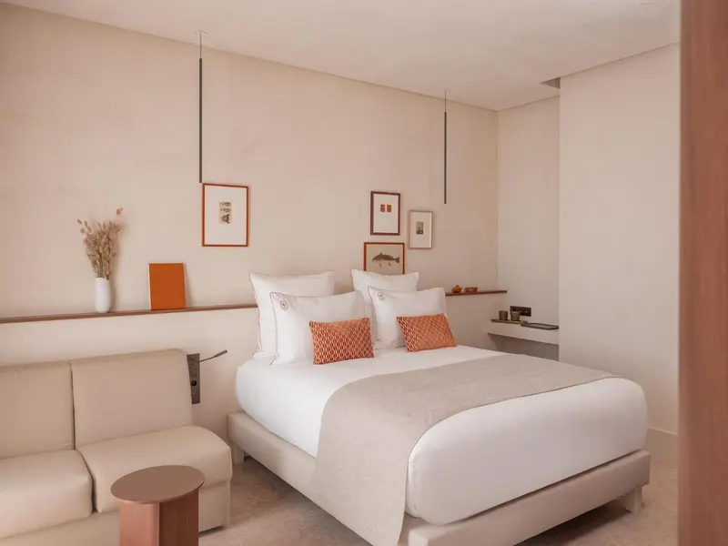 Une chambre lumineuse avec un grand lit et des coussins décoratifs.
