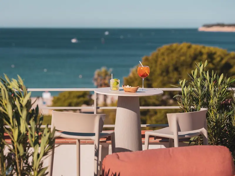 Une table avec des boissons fraîches sur une terrasse ensoleillée avec vue sur la mer.