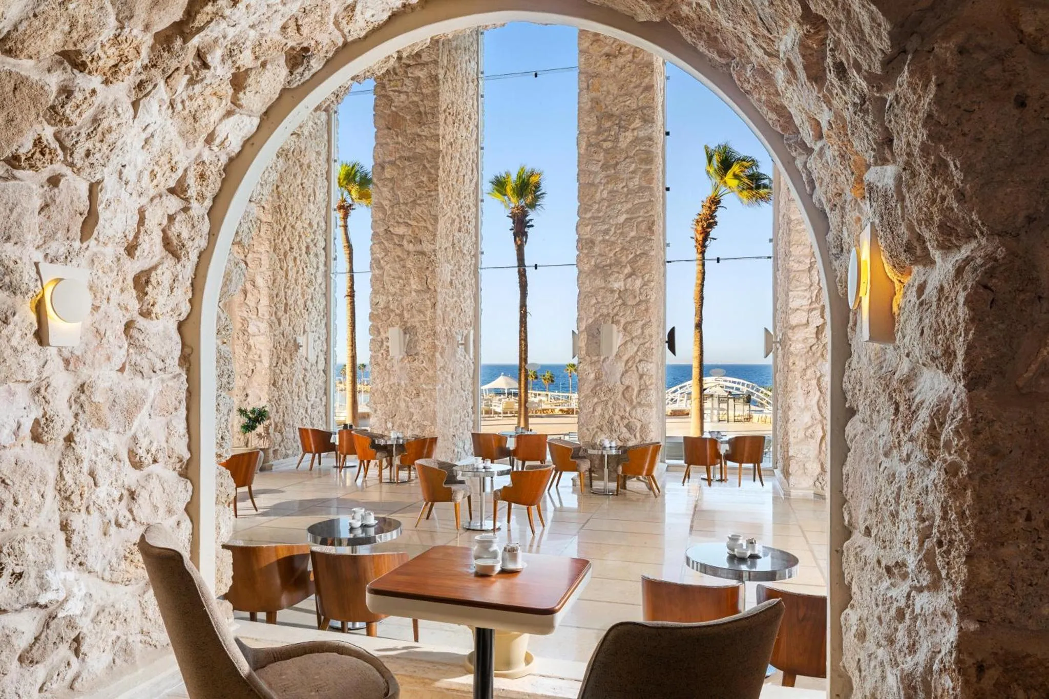 Une salle à manger lumineuse s'ouvre sur une vue sur la mer et la plage.