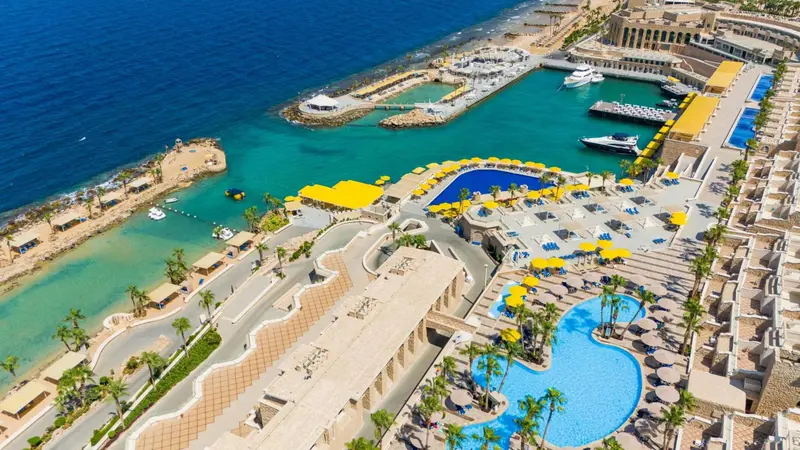 Vue aérienne d'un complexe hôtelier avec piscines et accès à la mer.