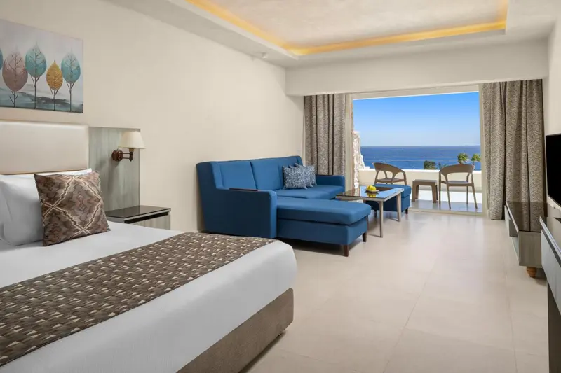 Chambre lumineuse avec canapé bleu et vue sur la mer.