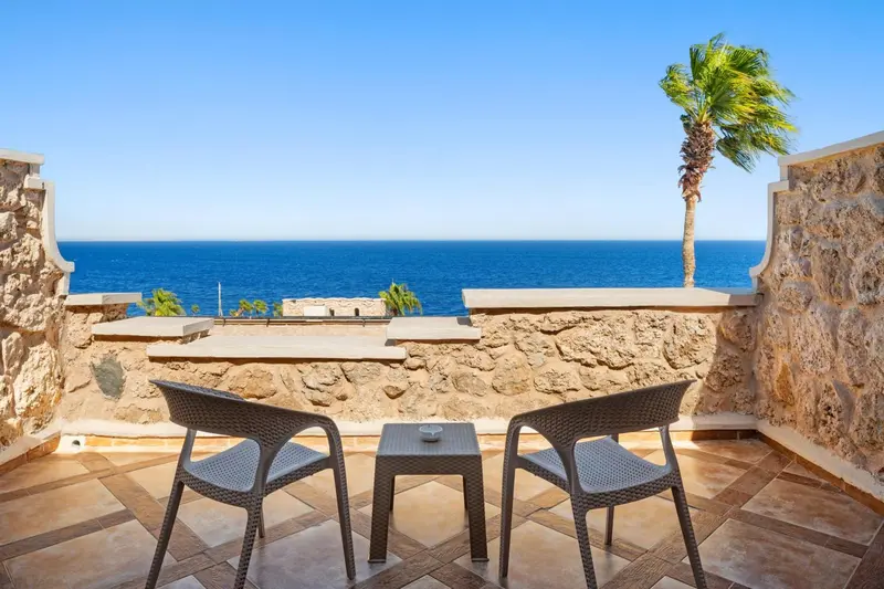 Terrasse avec mobilier en osier donnant sur la mer bleue.