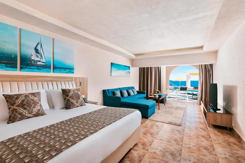Une chambre lumineuse avec un grand lit et un coin salon.