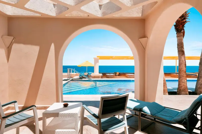 Deux fauteuils de jardin invitent à la détente face à une piscine et à la mer.