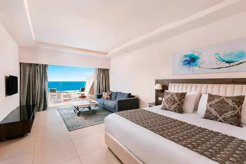 Une chambre lumineuse avec un canapé et un lit donnant sur la mer.