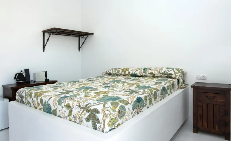 Une chambre lumineuse avec un lit recouvert d'une couette à motifs floraux.