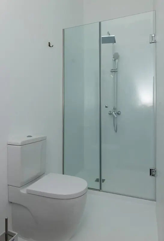 Une salle de bain moderne avec douche vitrée et toilettes.
