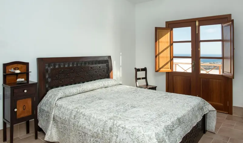 Une chambre lumineuse avec un grand lit recouvert d'une courtepointe.