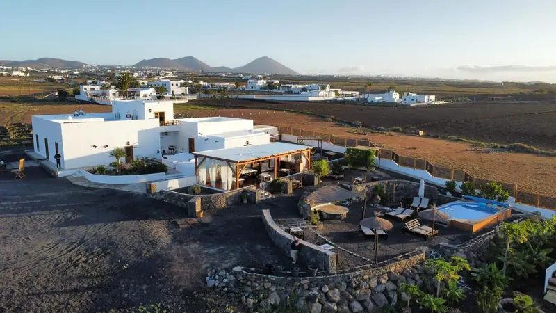 Vue aérienne d'un complexe hôtelier blanc avec piscine et végétation luxuriante.