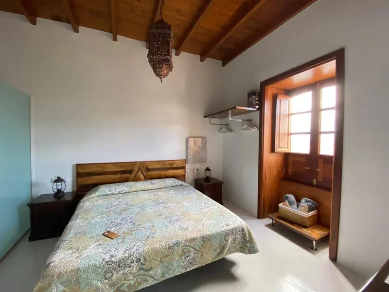 Une chambre lumineuse avec un grand lit et une fenêtre en bois.