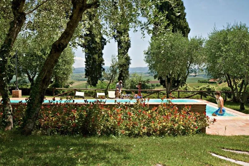 Une piscine rectangulaire bordée de verdure et de fleurs, avec des personnes se relaxant et se baignant.