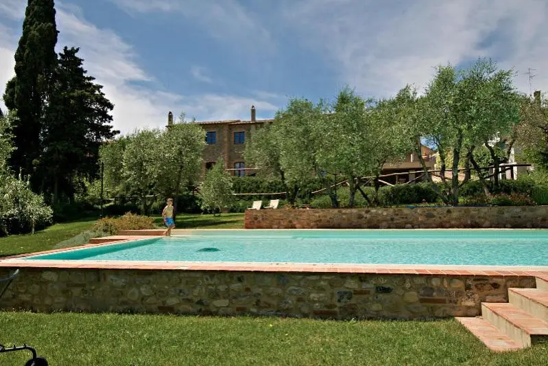 Une piscine rectangulaire bordée d'herbe et entourée de végétation luxuriante.
