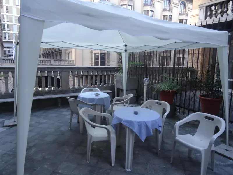 Terrasse ombragée avec tables et chaises en plastique.