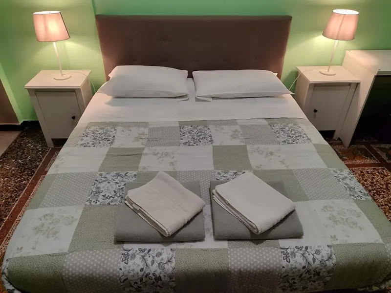 Une chambre lumineuse avec un grand lit recouvert d'une courtepointe.