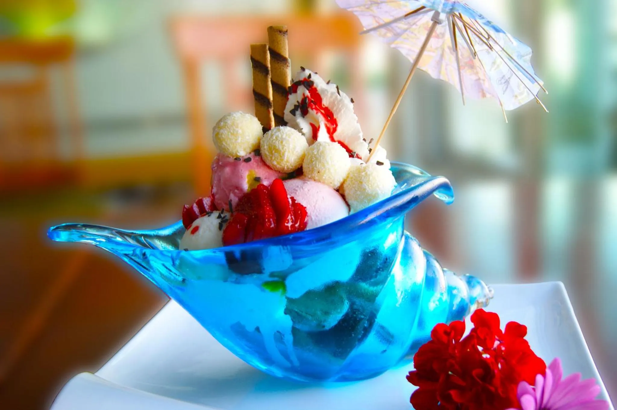 Une coupe de glace colorée est décorée de fruits et d'un parasol.