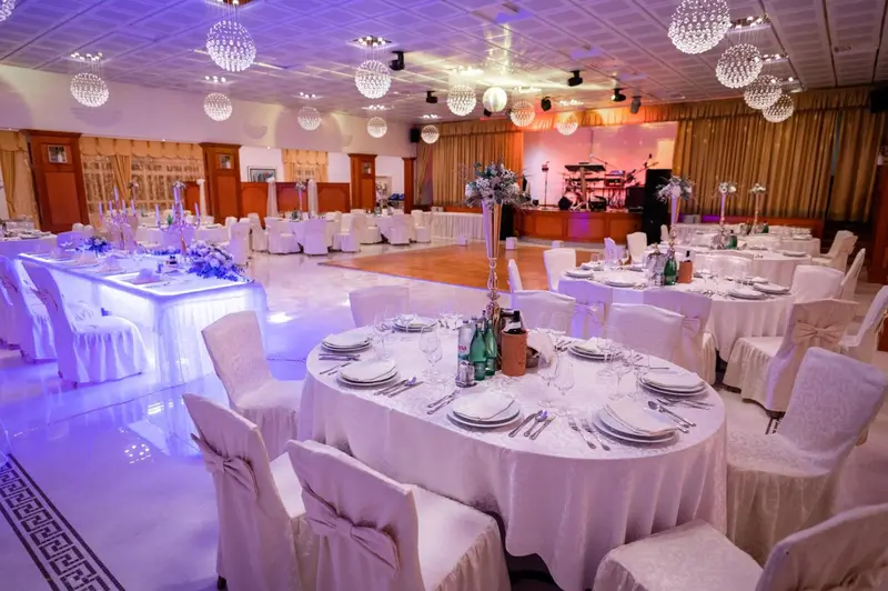 Une salle de réception lumineuse avec des tables dressées pour un événement.