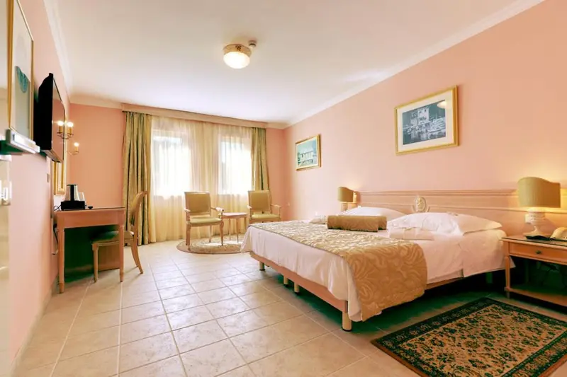 Une chambre lumineuse avec un lit double et deux fauteuils.