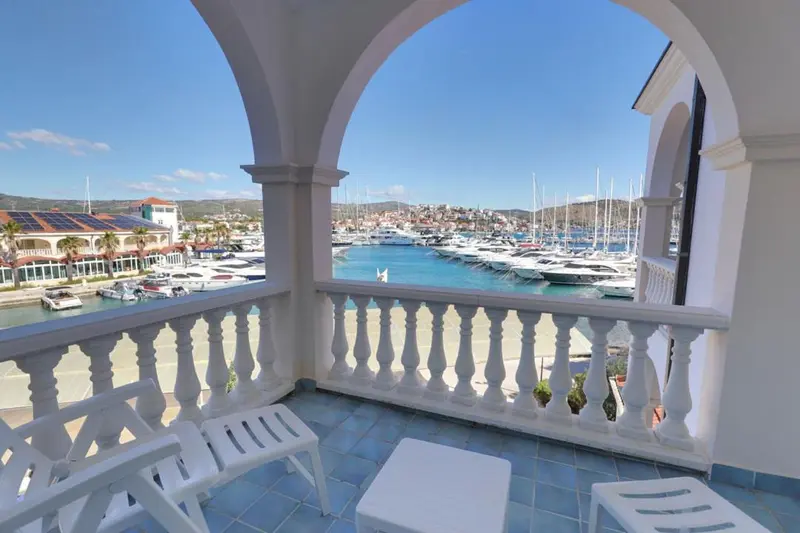 Vue sur un port de plaisance depuis une terrasse ensoleillée.