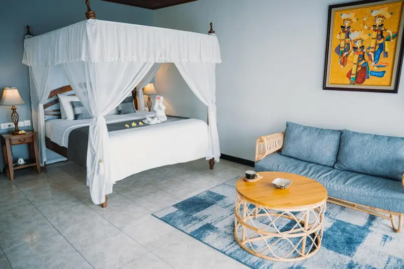 Une chambre lumineuse avec un lit à baldaquin et un coin salon.