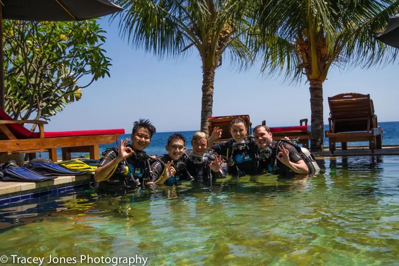 Groupe de personnes souriantes dans une piscine au bord de la mer.