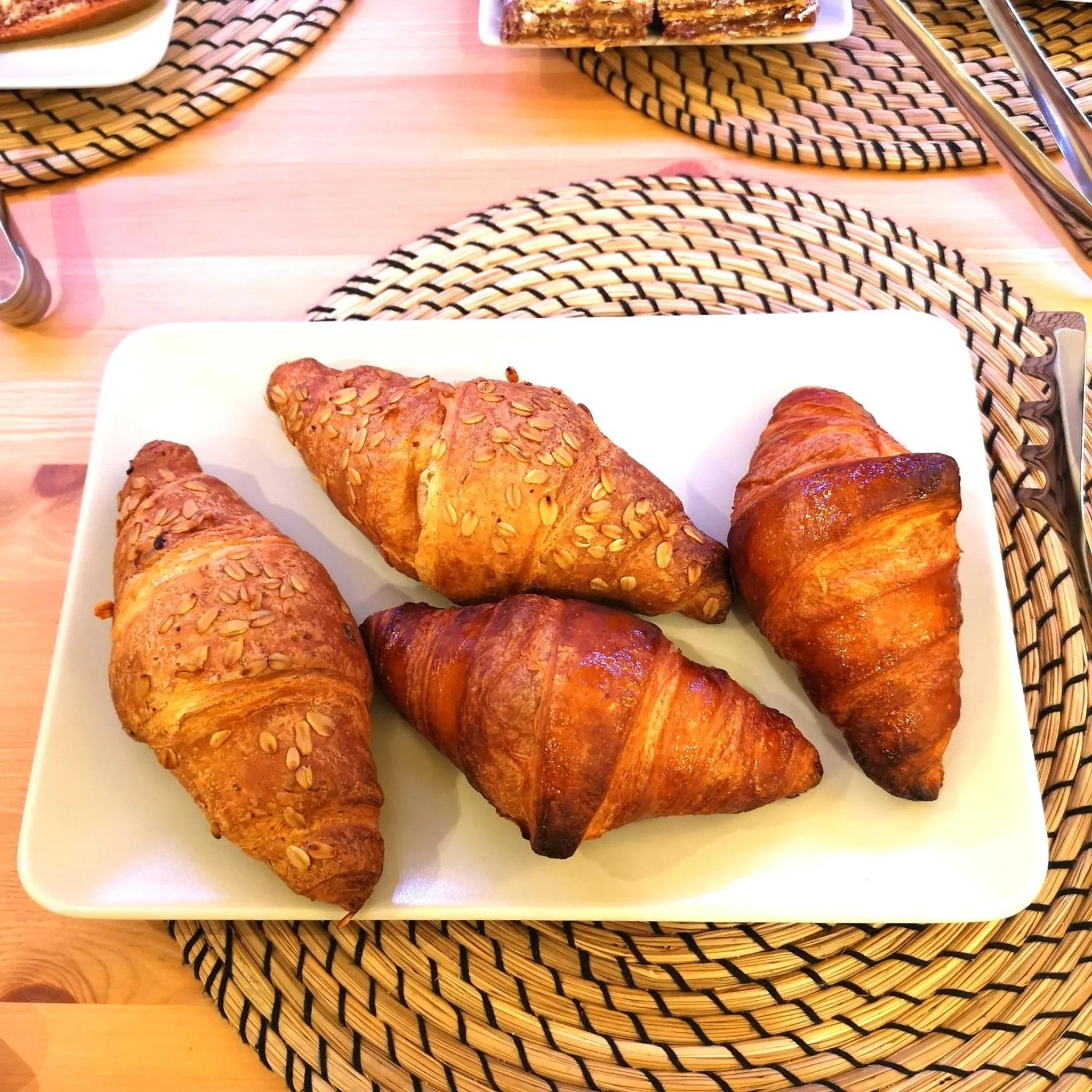 Assiette de croissants dorés sur une nappe en fibres naturelles.
