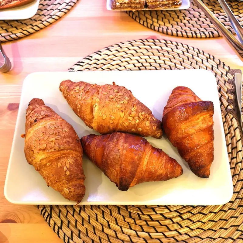 Assiette de croissants dorés sur une nappe en fibres naturelles.