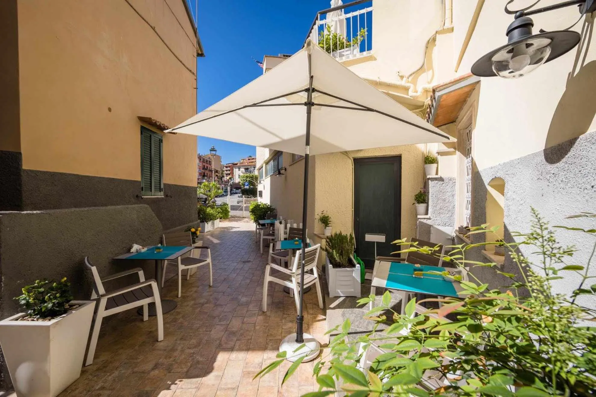 Terrasse ombragée avec tables et chaises en métal blanc.