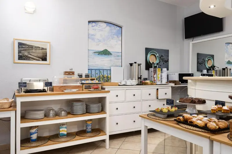 Un buffet propose des viennoiseries et des boissons chaudes dans une salle lumineuse.