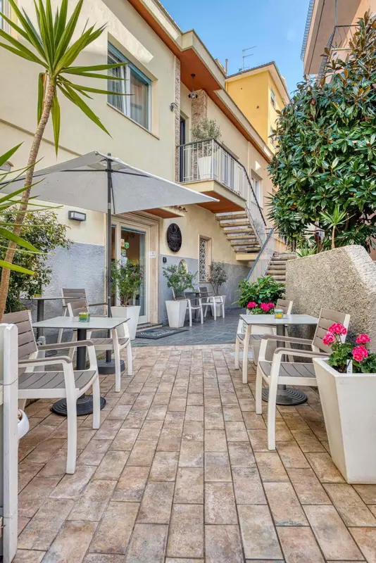 Terrasse carrelée avec mobilier de jardin et plantes en pots devant un bâtiment.