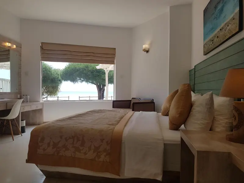 Une chambre lumineuse avec un grand lit et vue sur la mer.