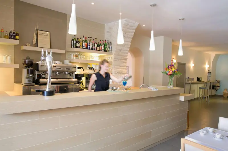 Une barmaid prépare un cocktail derrière un comptoir moderne.