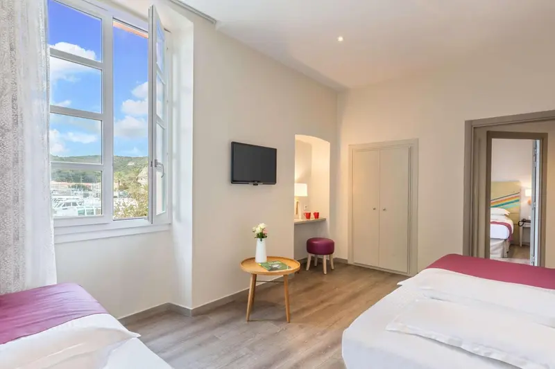 Une chambre lumineuse avec un lit et une fenêtre ouverte sur un paysage.