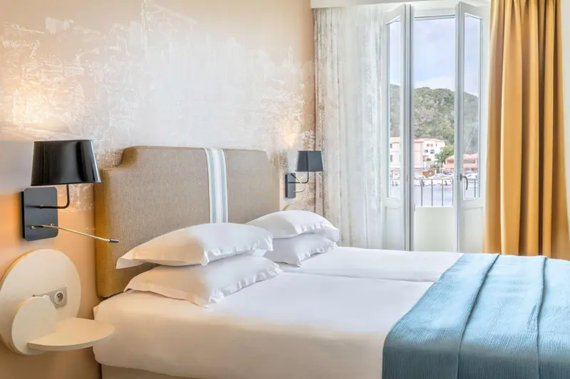 Une chambre lumineuse avec un grand lit et un accès à un balcon.