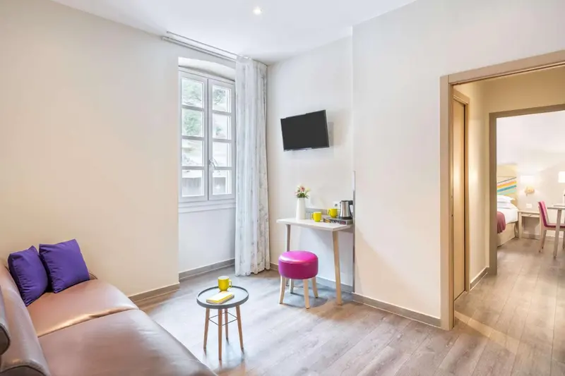 Une pièce lumineuse avec un canapé, une table basse et un bureau près d'une fenêtre.