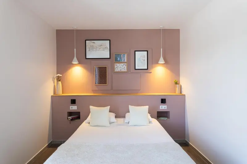 Une chambre lumineuse avec un grand lit et des tableaux décoratifs au mur.