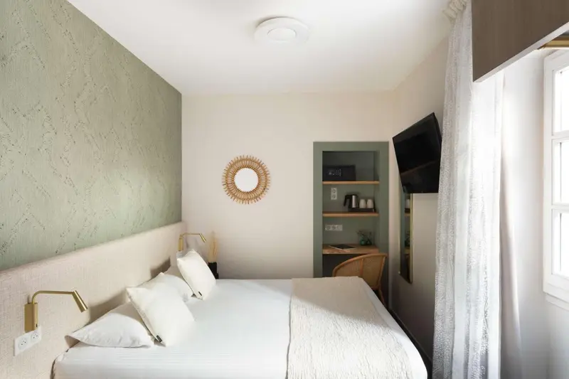 Une chambre lumineuse avec un lit double et une décoration sobre.