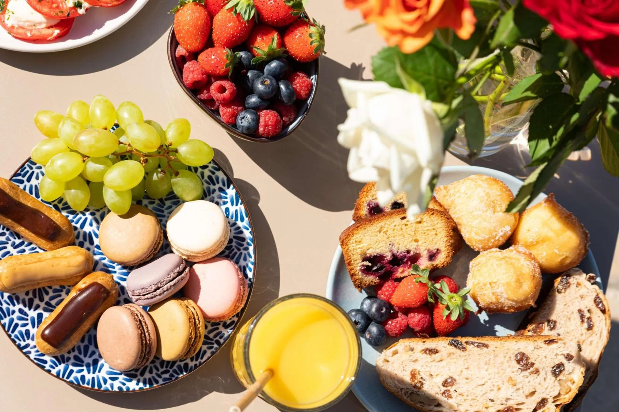 Nature morte de fruits frais, viennoiseries et jus d'orange sur une table.
