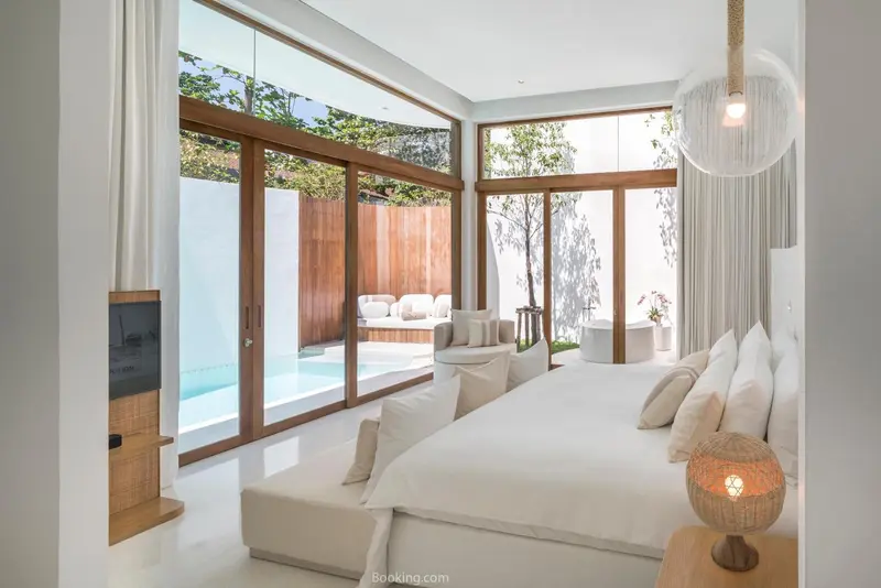 Chambre lumineuse avec un lit king-size et vue sur une piscine.