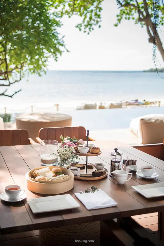 Une table en bois est dressée avec un petit-déjeuner face à la mer.