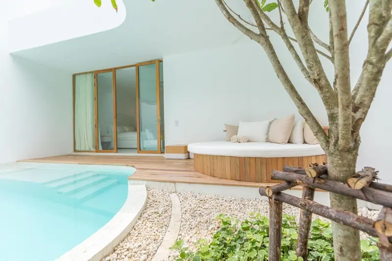 Espace de détente extérieur avec canapé circulaire et petite piscine.