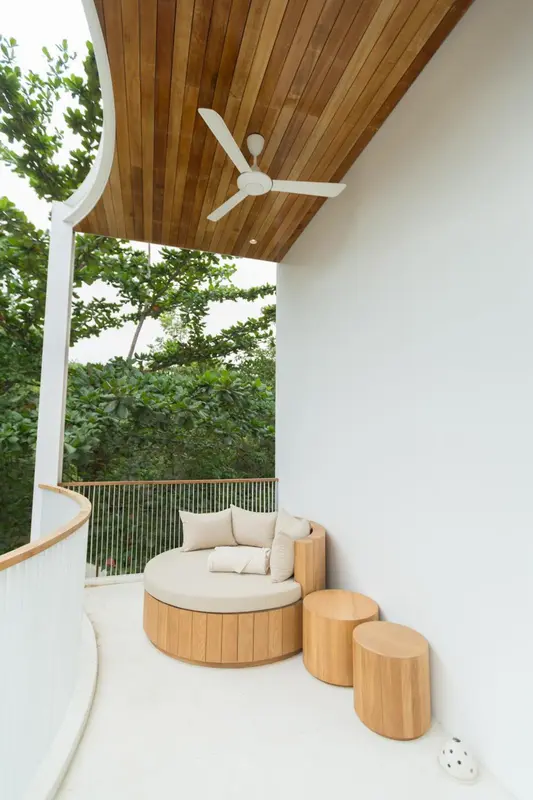 Espace de détente extérieur avec mobilier en bois clair et végétation luxuriante.