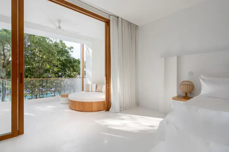 Une chambre lumineuse s'ouvre sur une terrasse avec un salon de jardin.