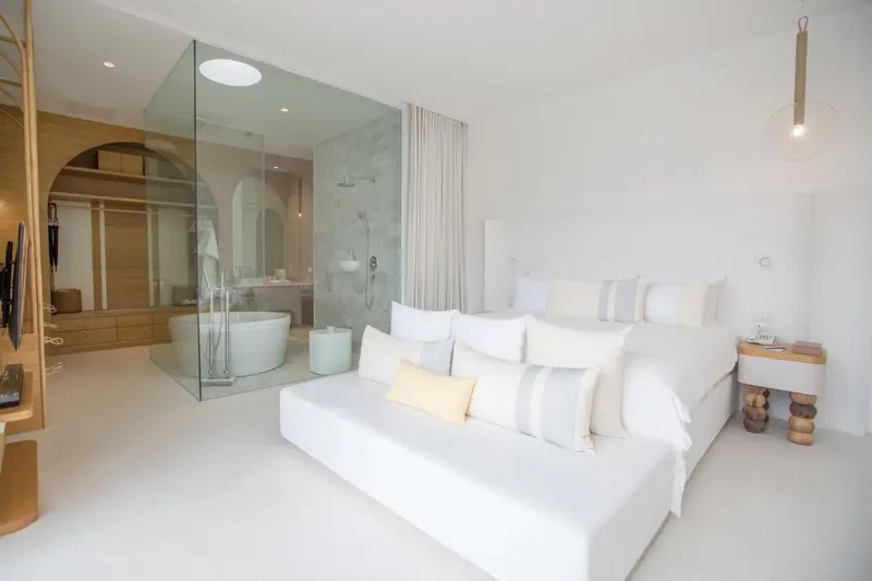 Une chambre lumineuse avec un grand lit et une salle de bain ouverte.