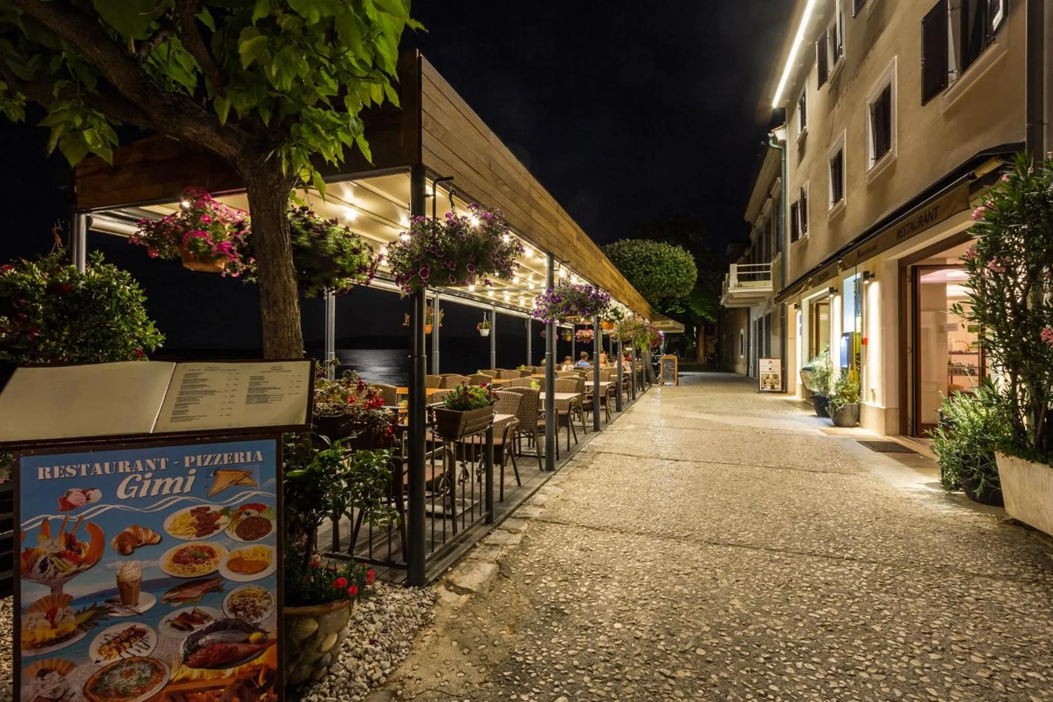 Terrasse de restaurant illuminée avec tables et chaises en bord de mer.