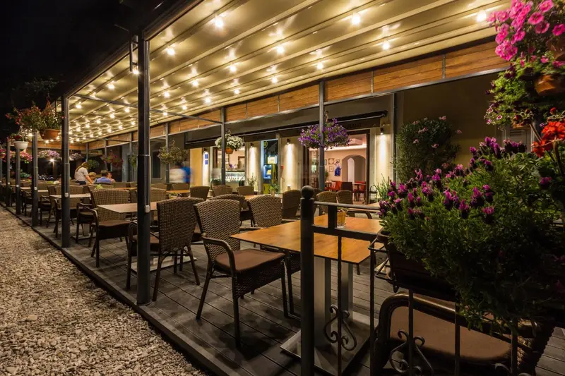 Terrasse illuminée avec tables et chaises disposées sur un sol en gravier.