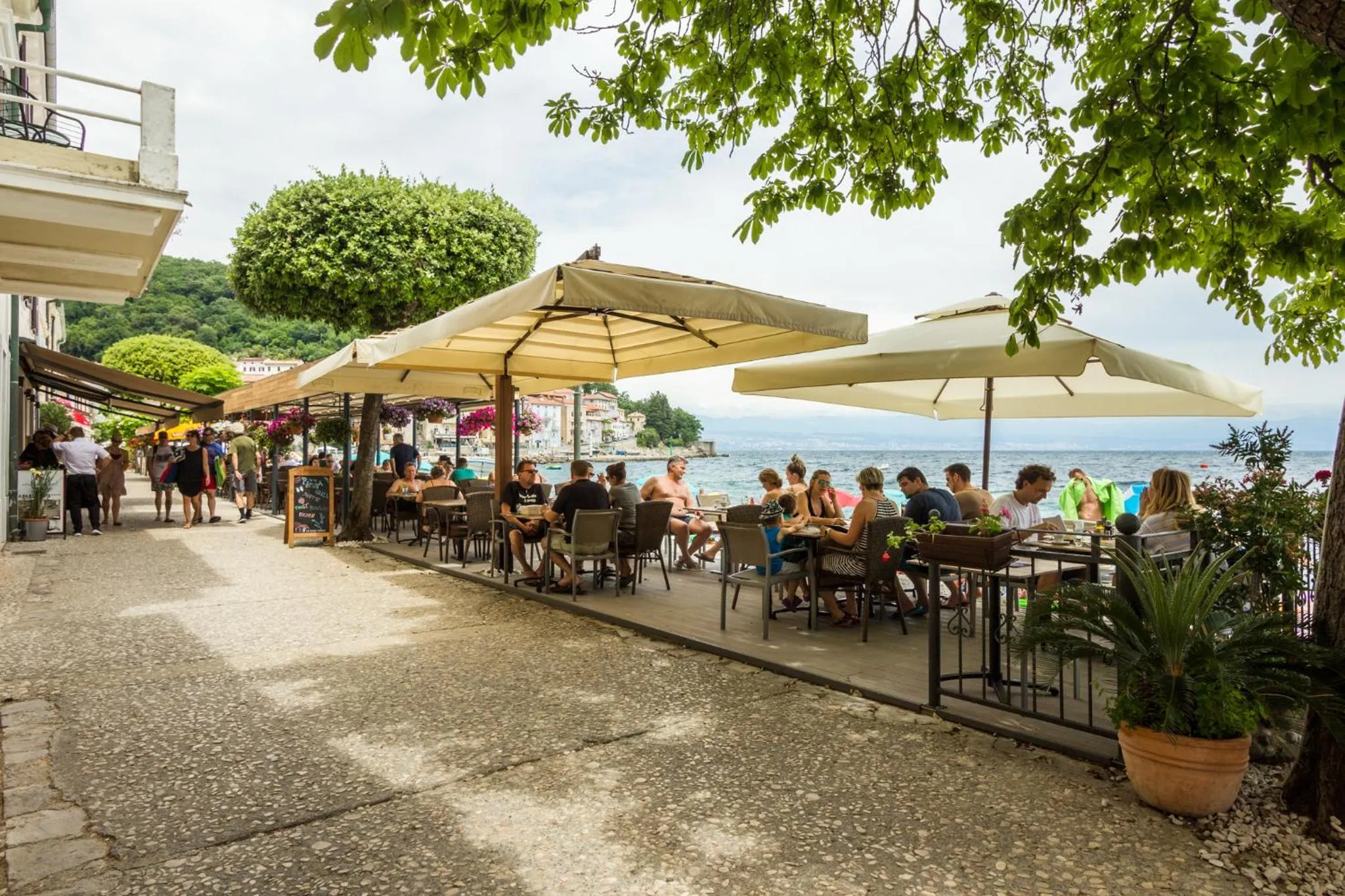 Terrasse ombragée avec tables et chaises en bord de mer.